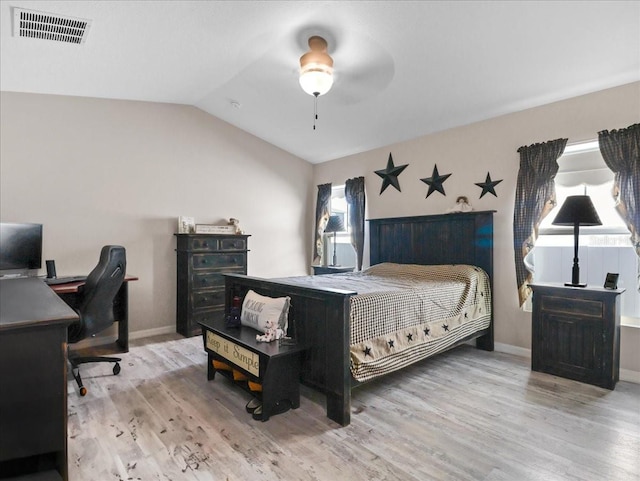 bedroom with lofted ceiling, wood finished floors, visible vents, and baseboards