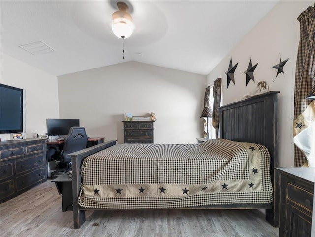 bedroom with ceiling fan, visible vents, vaulted ceiling, and wood finished floors