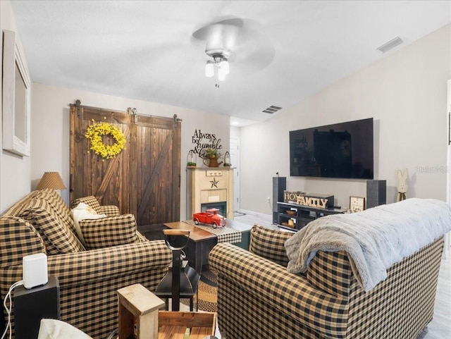 living area featuring a ceiling fan, visible vents, and a barn door