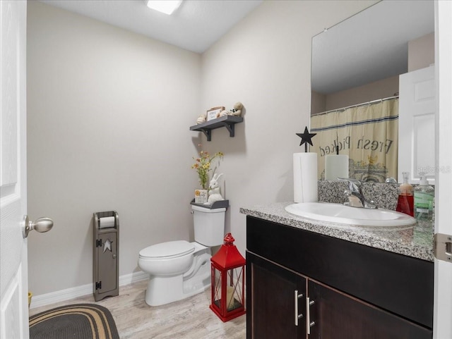 full bath with baseboards, vanity, toilet, and wood finished floors