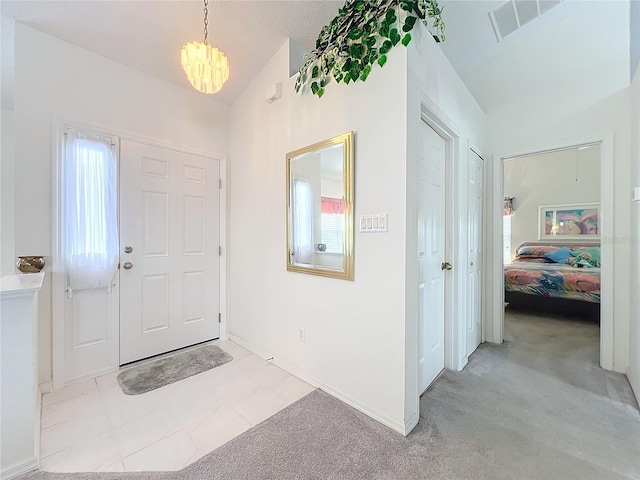 entryway with lofted ceiling, baseboards, a chandelier, and light colored carpet