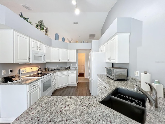 kitchen with light stone counters, white appliances, a sink, and visible vents