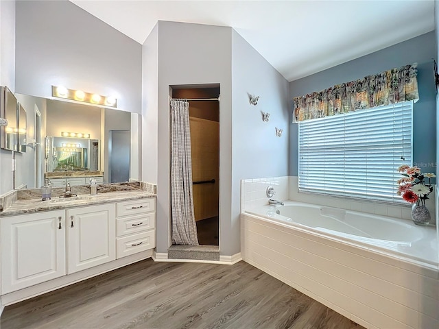 bathroom featuring a garden tub, wood finished floors, vanity, and a shower stall