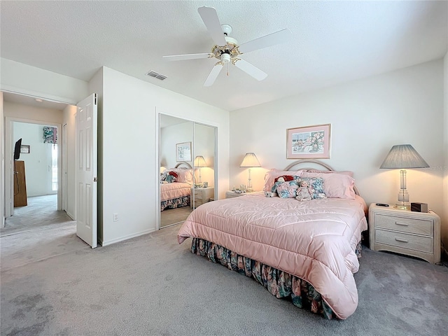 bedroom featuring a closet, visible vents, a ceiling fan, light carpet, and a textured ceiling