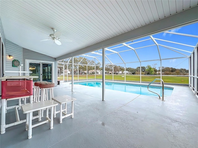 pool with a patio, glass enclosure, a lawn, and a ceiling fan