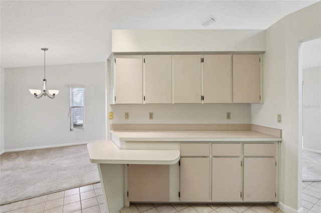 kitchen featuring light countertops, cream cabinetry, light carpet, and visible vents