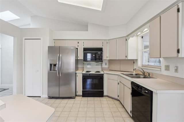 kitchen with lofted ceiling, black appliances, a sink, and light countertops