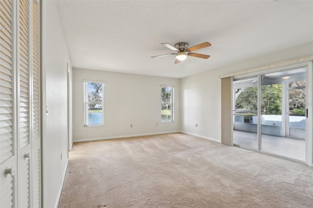 empty room featuring baseboards, a textured ceiling, a ceiling fan, and light colored carpet