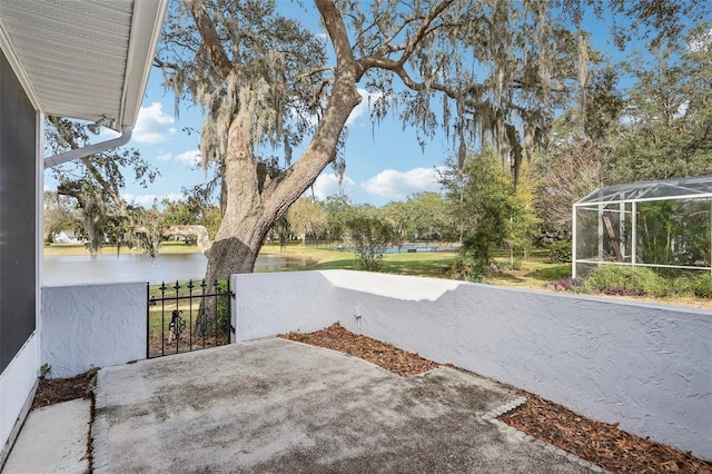 view of patio / terrace featuring a water view, glass enclosure, and fence