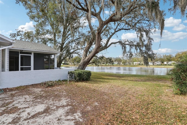 view of yard with a sunroom and a water view