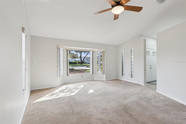 spare room featuring a ceiling fan, carpet, vaulted ceiling, and baseboards