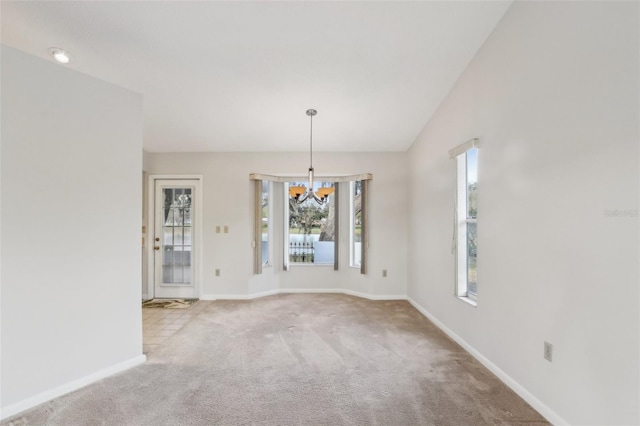 unfurnished dining area featuring baseboards, carpet floors, vaulted ceiling, and an inviting chandelier