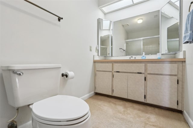 bathroom featuring toilet, a skylight, vanity, baseboards, and a shower with door