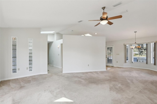 carpeted empty room featuring vaulted ceiling, ceiling fan with notable chandelier, visible vents, and baseboards