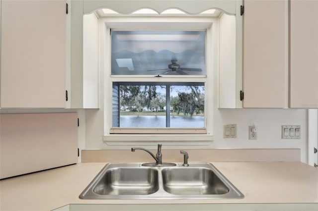 kitchen with white cabinets, ceiling fan, light countertops, and a sink