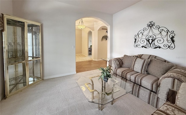 carpeted living area featuring arched walkways and baseboards