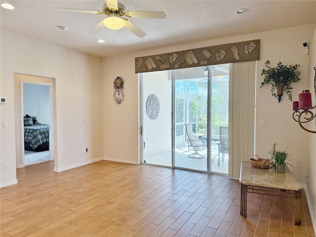 interior space with a ceiling fan, a textured ceiling, and light wood finished floors