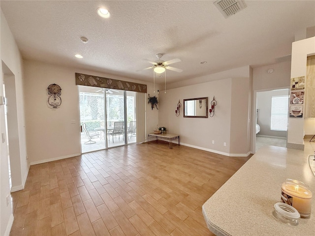 unfurnished room featuring light wood-type flooring, visible vents, and a textured ceiling