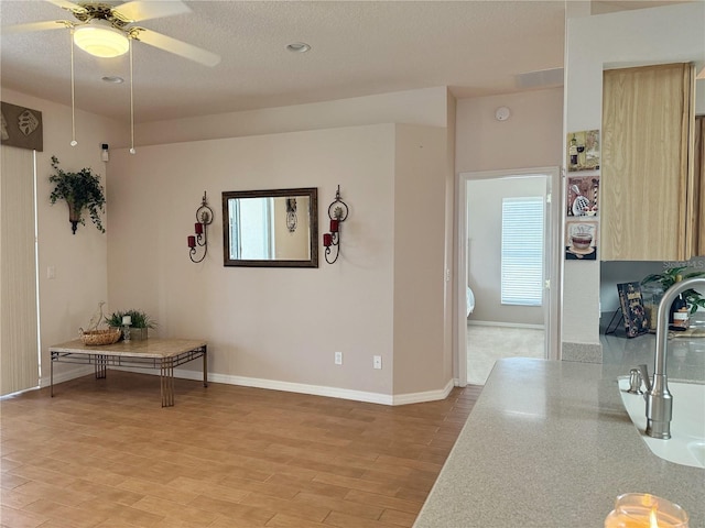 interior space with ceiling fan, plenty of natural light, light wood-style flooring, and baseboards