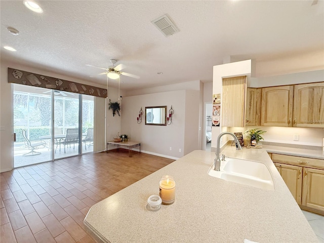 kitchen with light brown cabinets, visible vents, light countertops, and a sink