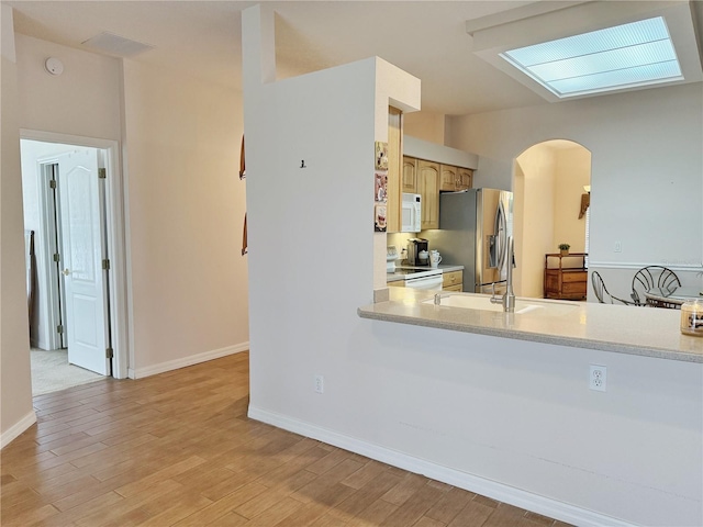 kitchen with arched walkways, light countertops, white appliances, and light wood-style flooring