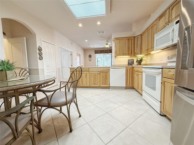 kitchen with light tile patterned flooring, a peninsula, white appliances, a skylight, and visible vents