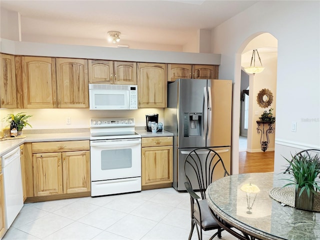 kitchen featuring white appliances, light brown cabinets, arched walkways, and light countertops