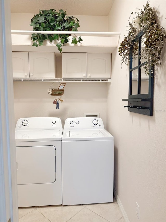 clothes washing area with cabinet space, independent washer and dryer, baseboards, and light tile patterned floors