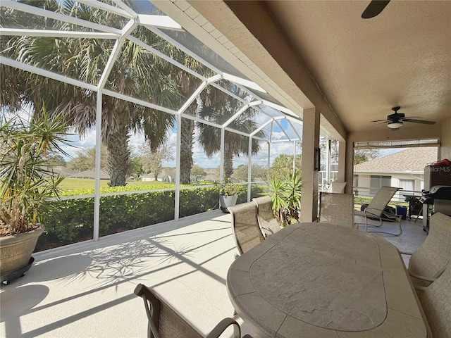 view of patio featuring glass enclosure, ceiling fan, and outdoor dining space