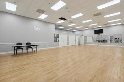 exercise area with a drop ceiling, wood finished floors, and baseboards