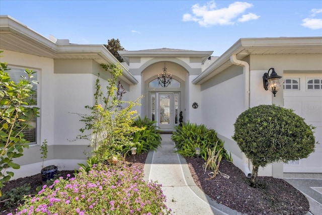 doorway to property with an attached garage and stucco siding