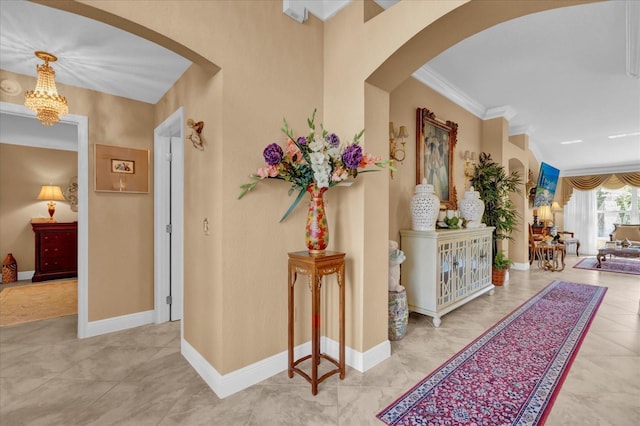 corridor featuring baseboards, arched walkways, and crown molding