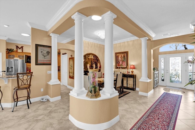 foyer entrance featuring baseboards, light tile patterned floors, decorative columns, and crown molding