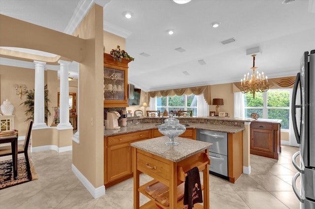 kitchen with arched walkways, a peninsula, visible vents, freestanding refrigerator, and ornate columns