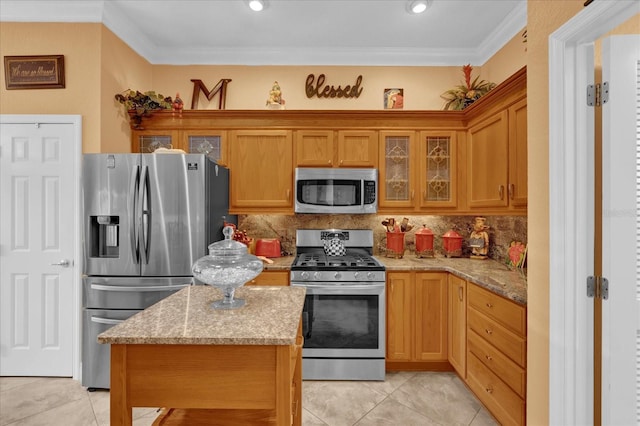 kitchen with stainless steel appliances, ornamental molding, backsplash, and light stone counters