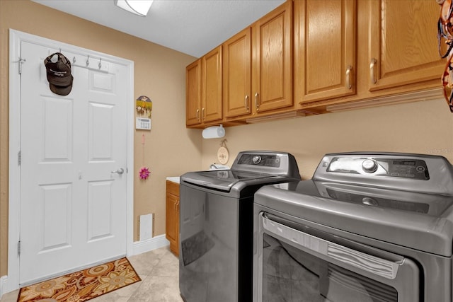 laundry area with cabinet space, washer and clothes dryer, baseboards, and light tile patterned floors