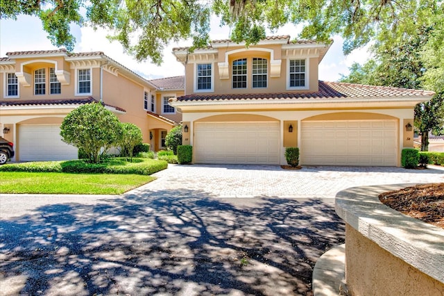 mediterranean / spanish-style house featuring decorative driveway, a tiled roof, and stucco siding