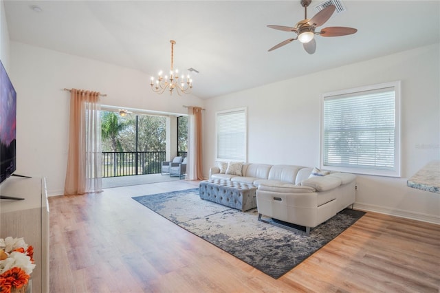 living room featuring ceiling fan with notable chandelier, lofted ceiling, visible vents, and wood finished floors