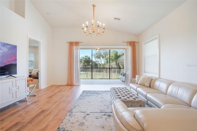 living room with an inviting chandelier, light wood-style flooring, visible vents, and high vaulted ceiling