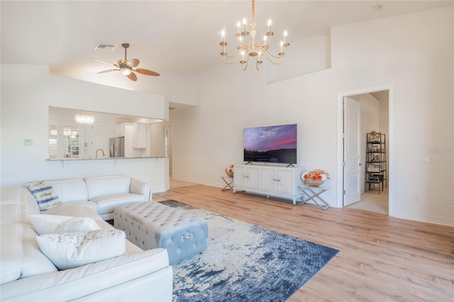 living area featuring light wood-style floors, visible vents, baseboards, and ceiling fan with notable chandelier