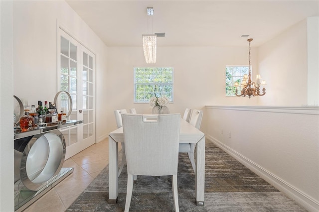 dining area featuring light tile patterned floors, baseboards, and a notable chandelier