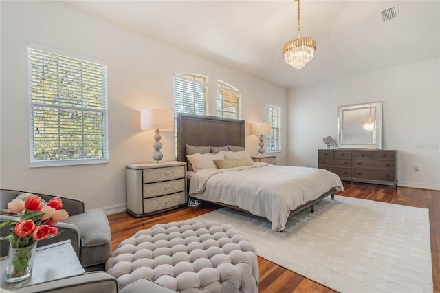 bedroom with an inviting chandelier, baseboards, visible vents, and wood finished floors