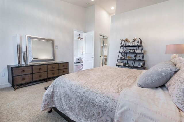 bedroom featuring carpet flooring, connected bathroom, and a towering ceiling