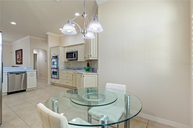 dining area with baseboards, ornamental molding, light tile patterned floors, arched walkways, and a notable chandelier