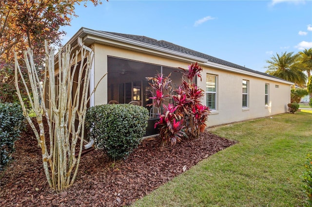 exterior space with stucco siding, a lawn, and a sunroom