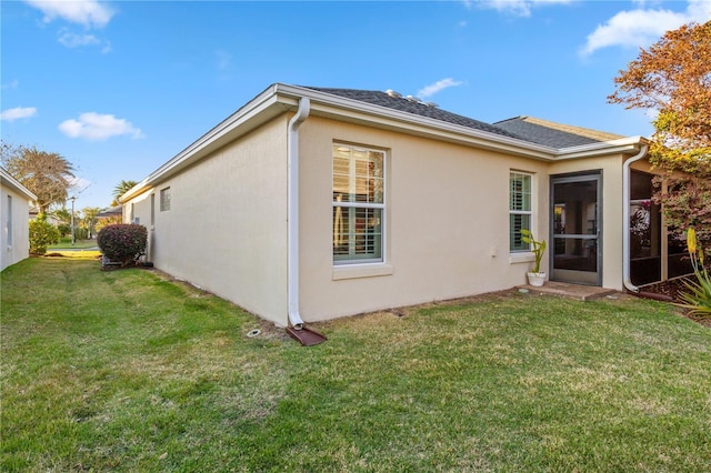 back of house featuring stucco siding and a lawn