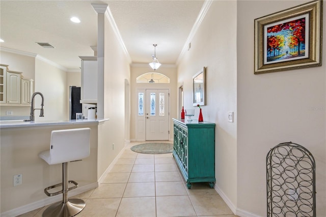 entrance foyer featuring light tile patterned floors, visible vents, baseboards, and ornamental molding