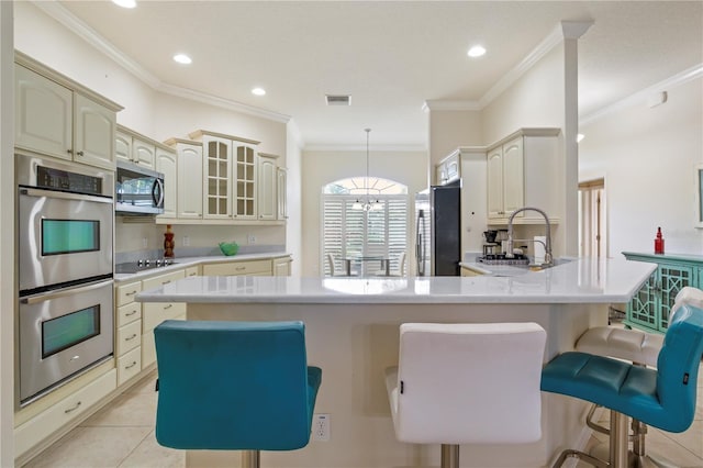 kitchen featuring ornamental molding, a kitchen breakfast bar, appliances with stainless steel finishes, light countertops, and light tile patterned floors