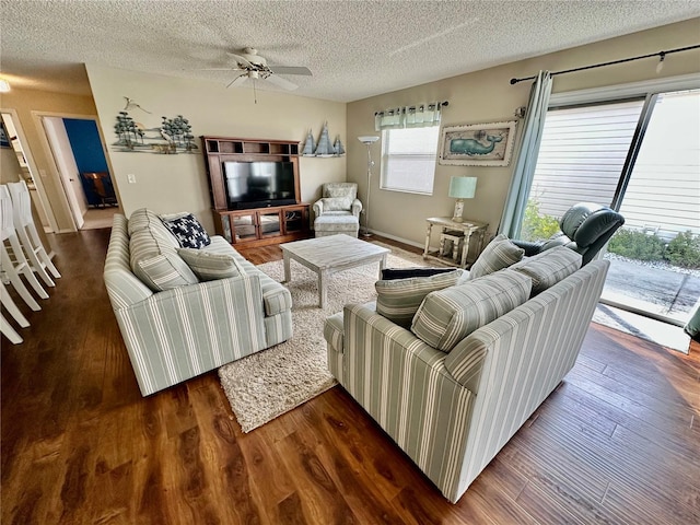 living area with dark wood-style floors, ceiling fan, and a textured ceiling