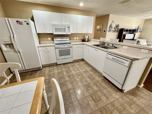 kitchen featuring white appliances, a peninsula, light countertops, white cabinetry, and a sink